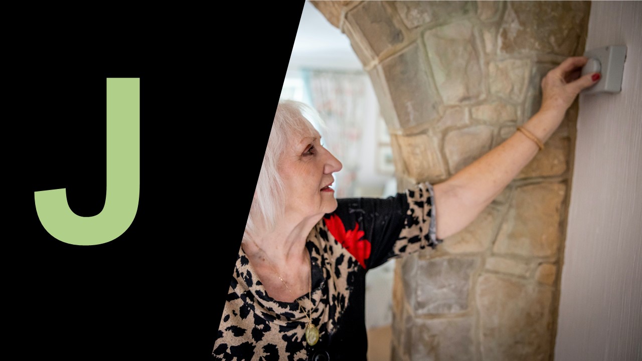 Older woman adjusting settings unit in home, large capital J